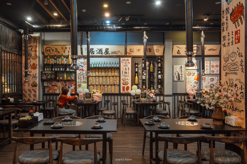 Quầy bar Izakaya với kệ rượu Sake và bảng menu gỗ Nhật Bản